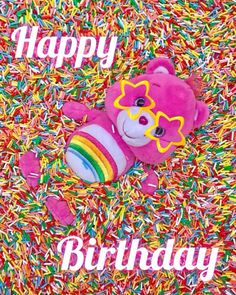 a pink teddy bear laying in sprinkles with the words happy birthday on it