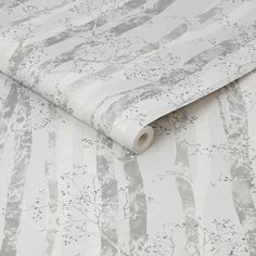 a white and grey wallpaper with trees on it's side, next to a roll of tape