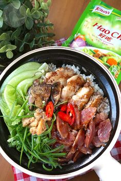 a pan filled with meat and vegetables on top of a table next to a bag of rice