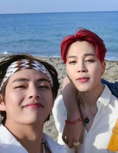 two young men standing next to each other on a beach