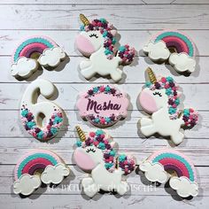 decorated cookies with unicorns and rainbows are arranged on a white wooden table top