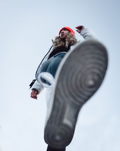 a woman wearing a red hat standing next to a pair of shoes