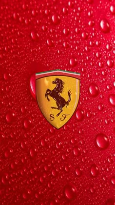 the ferrari logo is shown on a red surface with water droplets around it and there are also small drops of raindrops