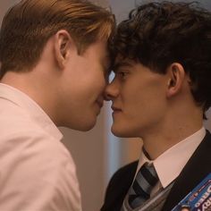 two men kissing each other while wearing ties