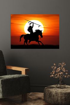 the silhouette of a man riding a horse with a spear in his hand at sunset