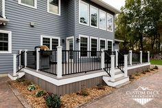 a gray house with black railings and white balconies on the front porch