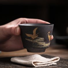 a person holding a cup with two birds on it