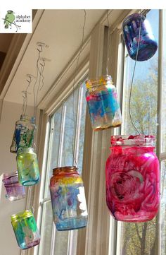 colorful glass jars hanging from a window sill