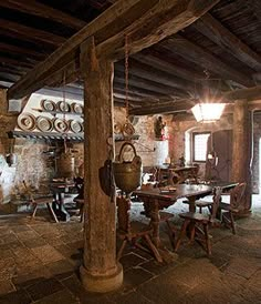 an old fashioned kitchen and dining room with stone flooring, exposed beams and wood ceiling