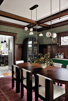 the dining room table is surrounded by white chairs and green wallpaper with floral designs