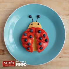 a blue plate topped with a ladybug cut in half on top of strawberries