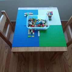 a lego table with two chairs and a plastic container filled with small blocks on it