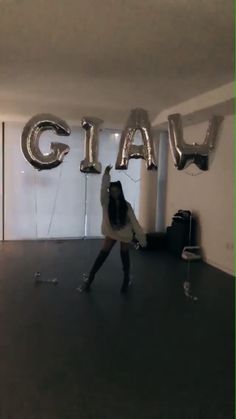 a woman is dancing in an empty room with balloons that spell out the word cia