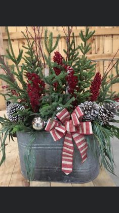 a potted plant with pine cones and evergreens in it, tied with a red ribbon