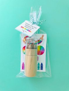 a pack of wooden crayons in a plastic bag on a blue background with a card