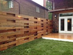 a large wooden fence in front of a house with white doors and lights on it