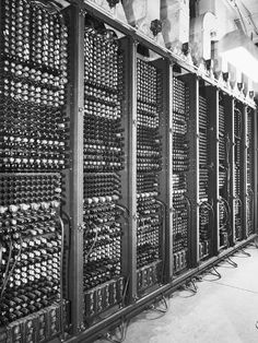 an old photo of several rows of computer equipment in a room with exposed pipes and wires