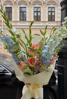 a bouquet of flowers sitting on top of a street light pole next to a black car