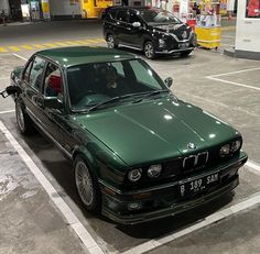 two green cars parked in a parking lot next to each other