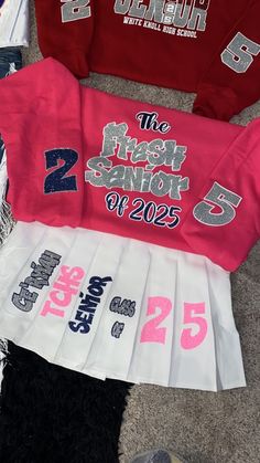 several shirts are laid out on the floor with numbers and letters printed on them, along with other items