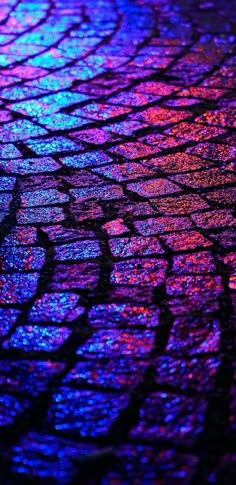 a close up view of a street with colorful lights on the pavement and cobblestones