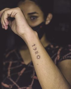 a woman with a tattoo on her arm holding the word love in front of her face