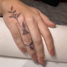 a woman's hand with a flower tattoo on her left thumb and ring finger