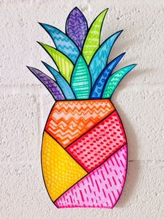 a colorful pineapple shaped wall hanging on a white brick wall in the shape of a geometric design