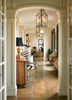 an open door leading to a living room filled with furniture and lamps on top of hard wood flooring