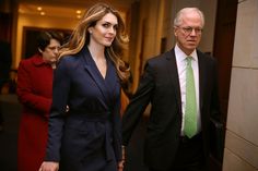 a woman in a blue suit and green tie walking next to an older man