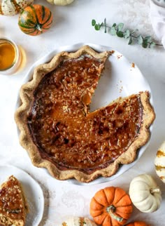 a pie sitting on top of a white plate next to small plates with pumpkins