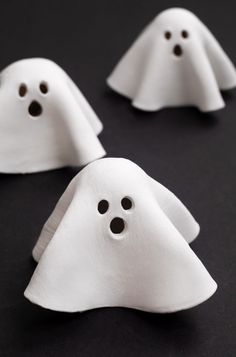 three white ghost - like objects on a black surface, with holes in the middle