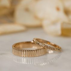 two gold wedding rings sitting on top of a table