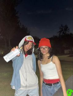 two young women standing next to each other in front of a dark sky at night