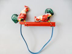 two colorful birds sitting on top of a blue cord attached to a red wall hook