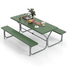 a green picnic table with two benches and plates of food on the table next to it