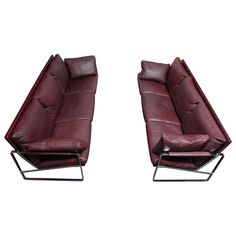 two red leather recliners sitting next to each other on top of metal frames