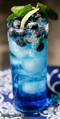 a blue drink with mint and lemon garnish