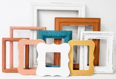 there are many different colored frames on the table together, including one with a white frame