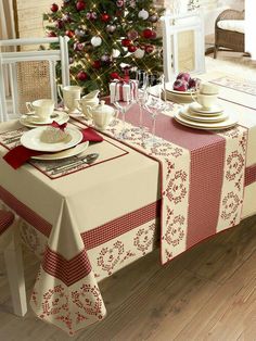 a christmas table setting with red and white decorations on the table, next to a small christmas tree