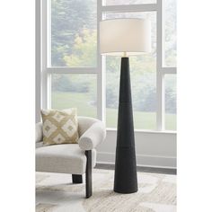 a black floor lamp with a white shade on it next to a chair and window