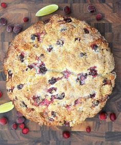 a cranberry cobbler on a cutting board surrounded by cherries and lemon wedges