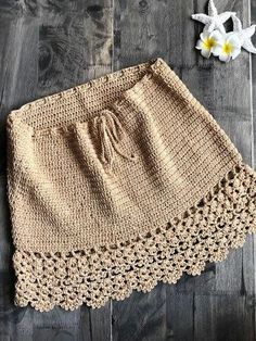 a crocheted skirt on a wooden floor next to flowers