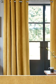 a living room with yellow curtains and a rug on the floor next to a coffee table