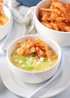 two white bowls filled with soup and some potato wedges next to each other on plates