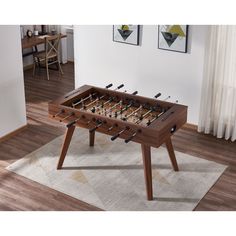 a wooden foosball table sitting on top of a rug in a living room