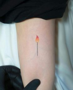 a woman's arm with a small fire stick tattoo on the left inner arm