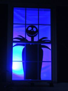 a window with a silhouette of a jack skellingy pumpkin in front of it