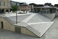 an empty parking lot with stairs leading up to the building and people walking around it