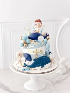 a blue and white cake with a little boy on top